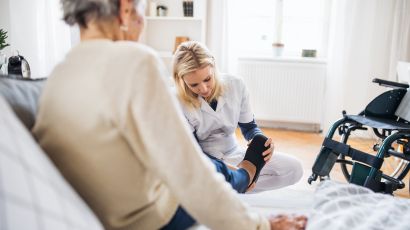 Pflegekraft massiert den Fuß einer sitzenden älteren Frau